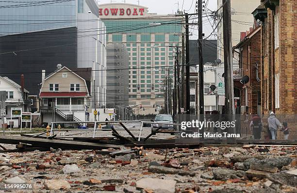 People walk past debris in the area where a 2000-foot section of the "uptown" boardwalk was destroyed by flooding from Hurricane Sandy with the...