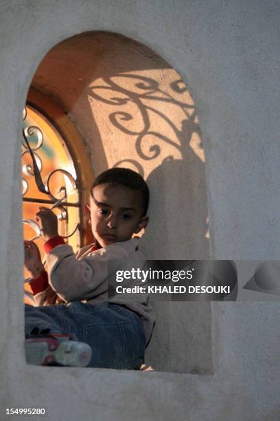 An Egyptian Christian Coptic boy sits in the bay of a window as he watches people gathering at the final resting place of Coptic Pope Shenuda III,...