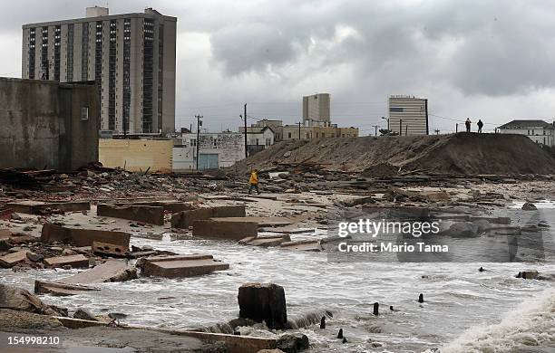 People stand on a mound of construction dirt to view the area where a 2,000-foot section of the "uptown" boardwalk was destroyed by flooding from...