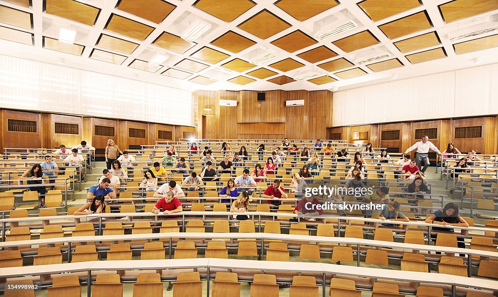 University amphitheatre full of students doing exam.