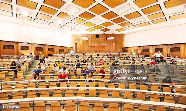 university amphitheatre full of students doing exam. - university lecture stock pictures, royalty-free photos & images