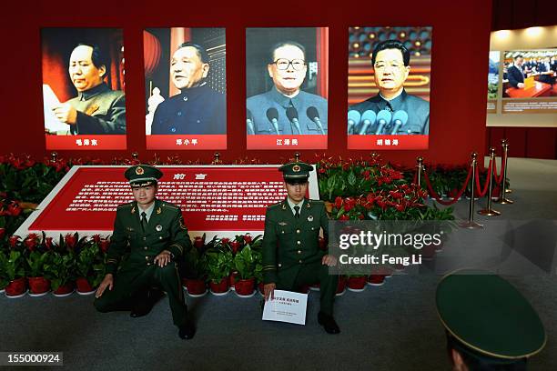 The paramilitary policemen pose for photo in front of the portraits of China's President Hu Jintao and former President Jiang Zeming as visiting an...