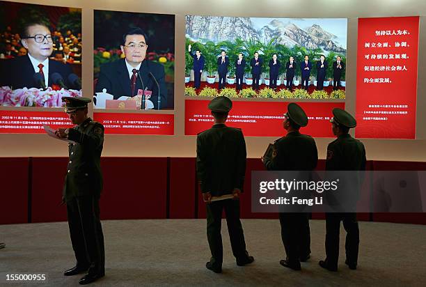 The paramilitary policemen pose for photo in front of the portraits of China's President Hu Jintao and former President Jiang Zeming as visiting an...