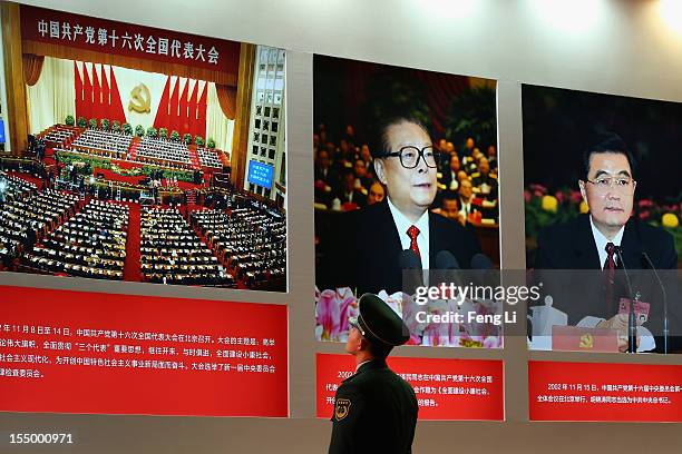 Paramilitary policeman passes the portraits of China's President Hu Jintao and former President Jiang Zeming as visiting an exhibition entitled...