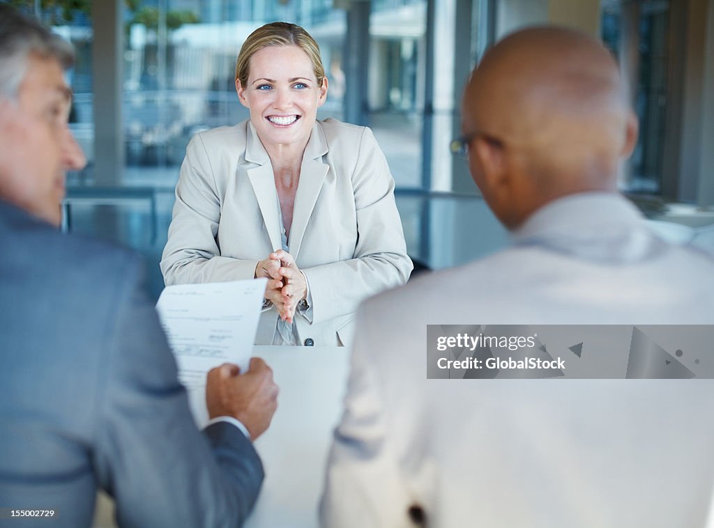 Smiling business woman sitting in front of interviewers