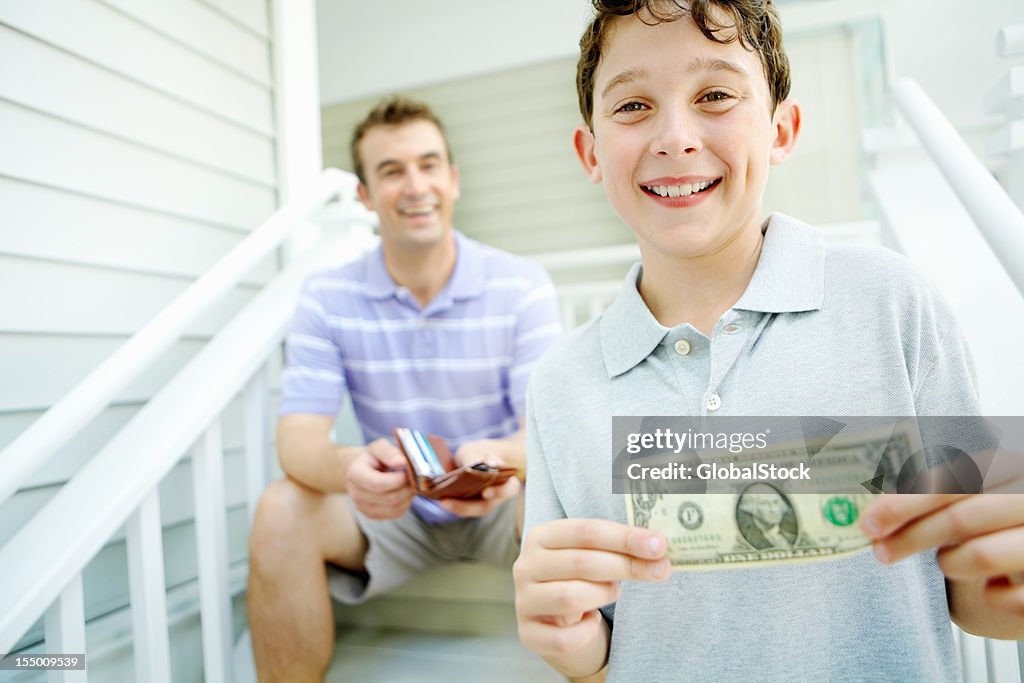 Smiling boy receives pocket money from his dad