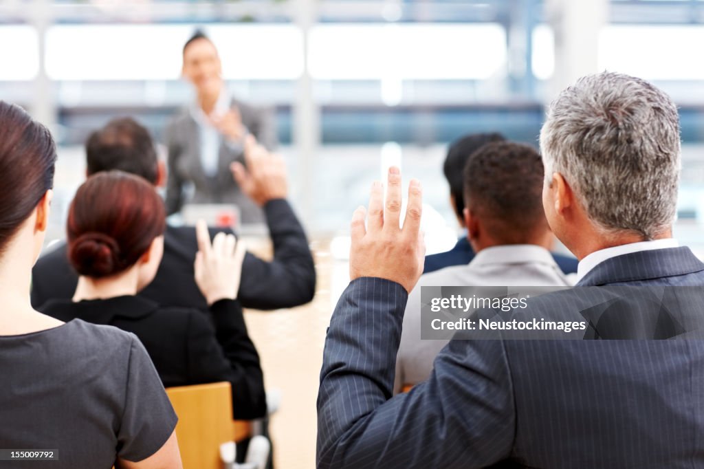 Homme d'affaires soulevant ses mains lors d'une conférence