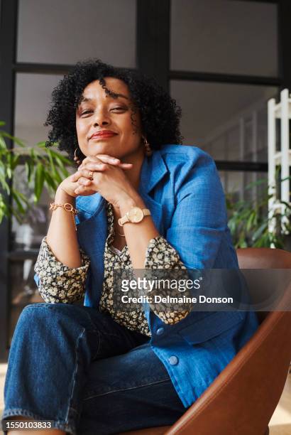 mature creative business woman sitting with a smile. stock photo - floral pattern trousers stock pictures, royalty-free photos & images