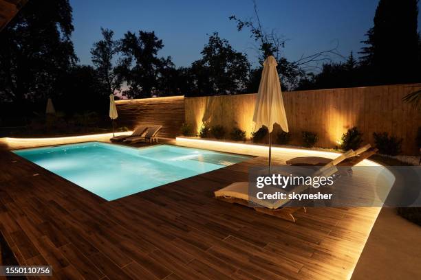 luxury patio with a pool at night. - deck stock pictures, royalty-free photos & images