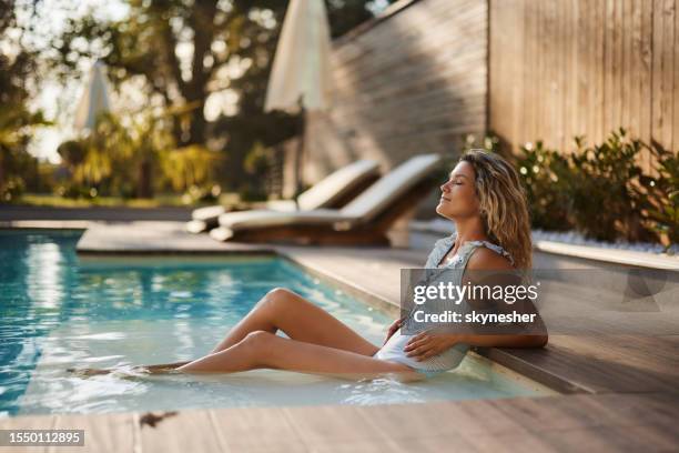 donna sorridente che gode in giornata estiva in piscina. - bordo piscina foto e immagini stock