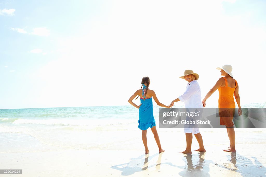 Senior woman walking with daughter and granddaughter on the beach