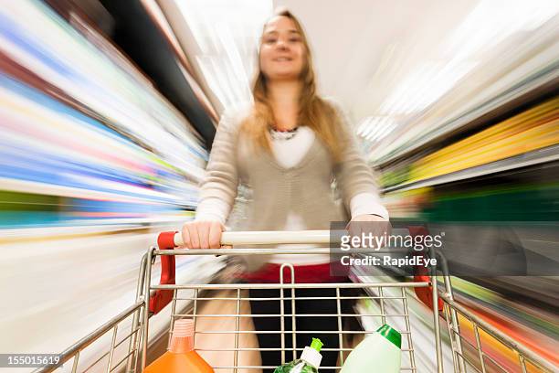 frau führt durch supermarkt-einkaufswagen mit mehrfarbigen motion blur - supermarket trolley female stock-fotos und bilder