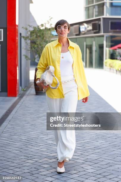 Swaantje Taube, wearing white pants, a white top, a yellow blouse, white pumps , a chain belt and a white bag, seen at the Marcel Ostertag Show...