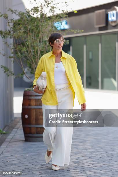 Swaantje Taube, wearing white pants, a white top, a yellow blouse, white pumps , a chain belt and a white bag, seen at the Marcel Ostertag Show...