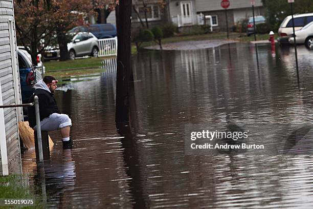 Man smokes a cigarette while watching flood waters caused by Hurricane Sandy from his driveway on October 30, 2012 in New York City. The storm has...