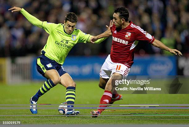 Mathew Lowton of Aston Villa is challenged by Gary Roberts of Swindon Town during the Capital One Cup Fourth Round match between Swindon Town and...