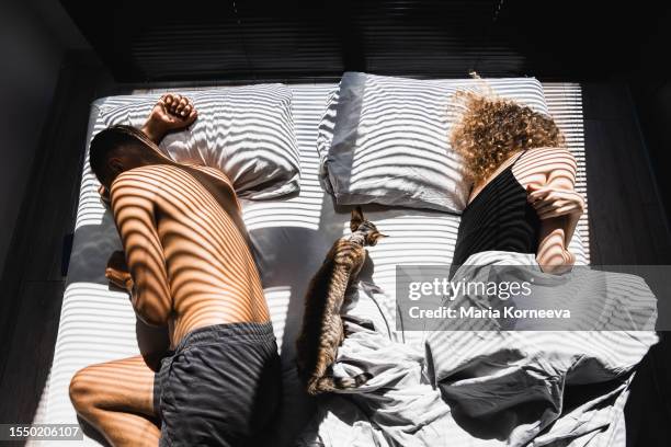 middle-aged couple after a quarrel lies back-to-back on the bed. - breaking apart stock pictures, royalty-free photos & images