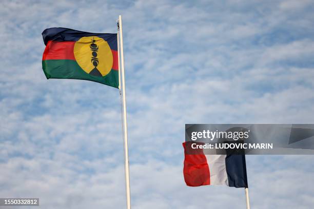 The New Caledonia flag flutters in the wind beside the French flag in Noumea on July 24, 2023 ahead of the arrival of France's President Emmanuel...