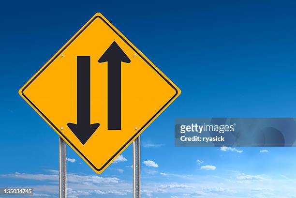 two way road sign showing opposing directions on blue sky - highway stock pictures, royalty-free photos & images