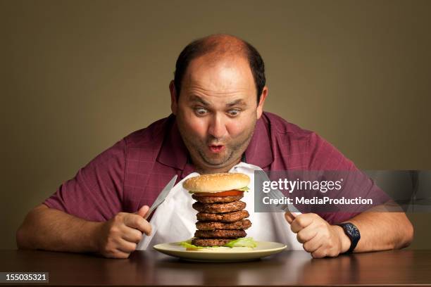 man eating a burger with six patties - gehaktbal stockfoto's en -beelden