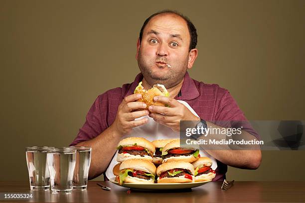 hombre comiendo numerosas hamburguesas - over eating fotografías e imágenes de stock