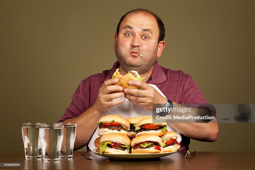 Man eating many burgers