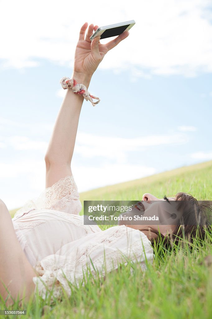 Woman lying on grass holding a smartphone