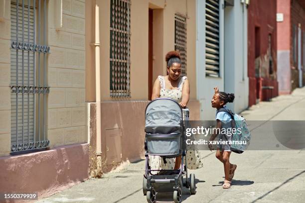 mother and young daughter conversing on the way to school - pushing stock pictures, royalty-free photos & images