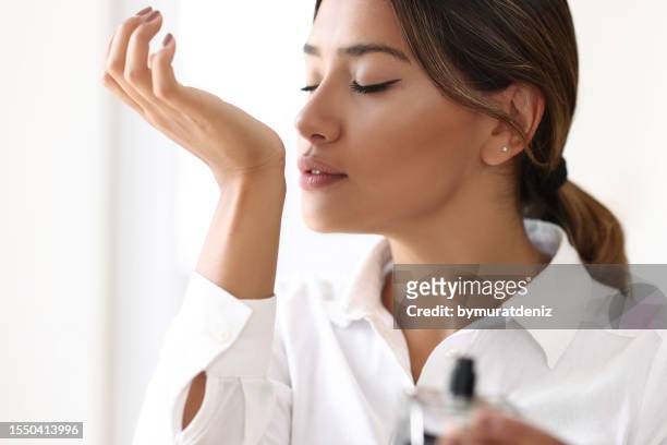 mujer probando perfume olfateando - oler fotografías e imágenes de stock