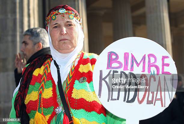 Protester in traditional Kurdish dress holds a sign reading "Die Erdogan" in Turkish while demonstrating in front of the Brandenburg Gate against the...