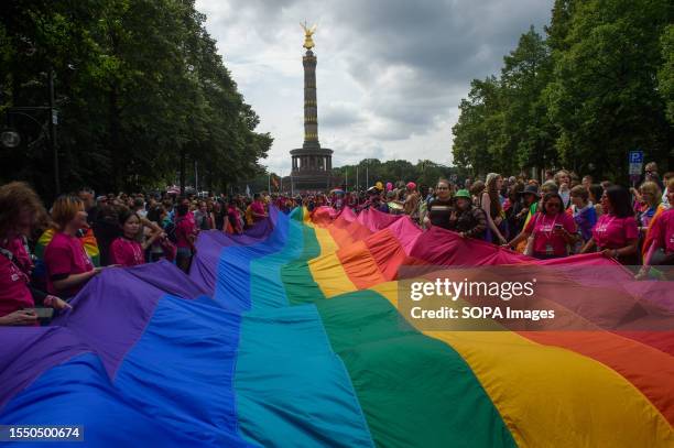 People march with huge pride flag during the pride parade. Berlin Christopher Street Day or Berlin Pride Parade is an annual demonstration in Berlin...