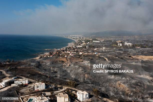 An aerial view shows smoke billowing in background of Kiotari village, on the island of Rhodes on July 24, 2023. Tens of thousands of people have...