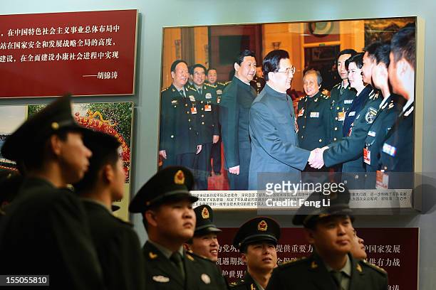 Soldiers passes the picture of China's President Hu Jintao and Vice President Xi Jinping as visiting an exhibition entitled "Scientific Development...