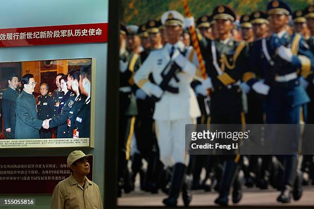 Man passes the picture of China's President Hu Jintao and Vice President Xi Jinping as visiting an exhibition entitled "Scientific Development and...