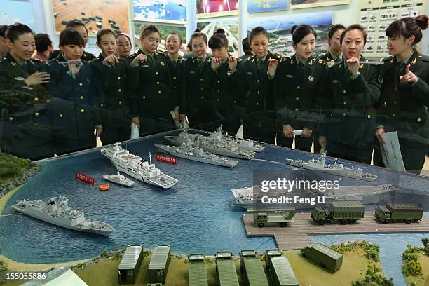 Female soldiers look at China's warship models as visiting an exhibition entitled "Scientific Development and Splendid Achievements" before the18th...