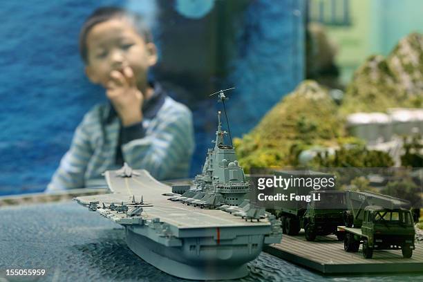Chinese little boy looks at the model of China's first aircraft carrier as visiting an exhibition entitled "Scientific Development and Splendid...