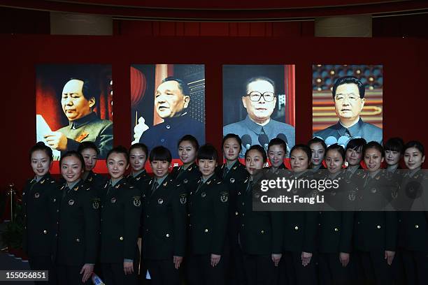 Female soldiers pose for photos in front of the portraits of China's President Hu Jintao and former President Jiang Zemin as visiting an exhibition...