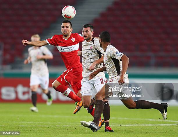 Vedad Ibisevic of Stuttgart is challenged by Florian Mohr and Christopher Avevor of St. Pauli during the second round match of the DFB Cup between...