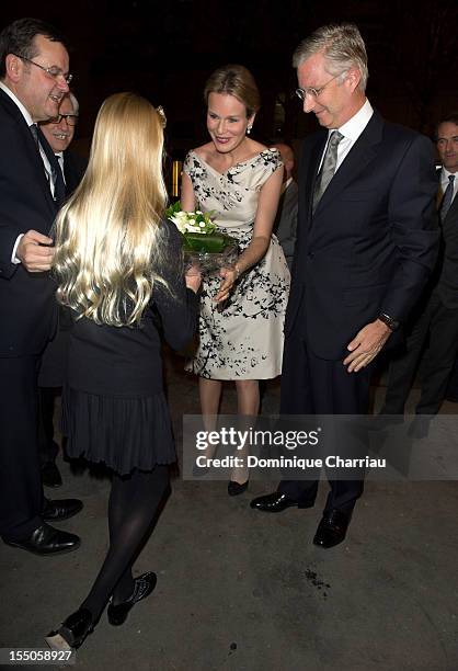 Young girl hands a bouquet of flowers to Princess Mathilde and Prince Philippe of Belgium as they arrive at Theatre des Champs-Elysees on October 31,...