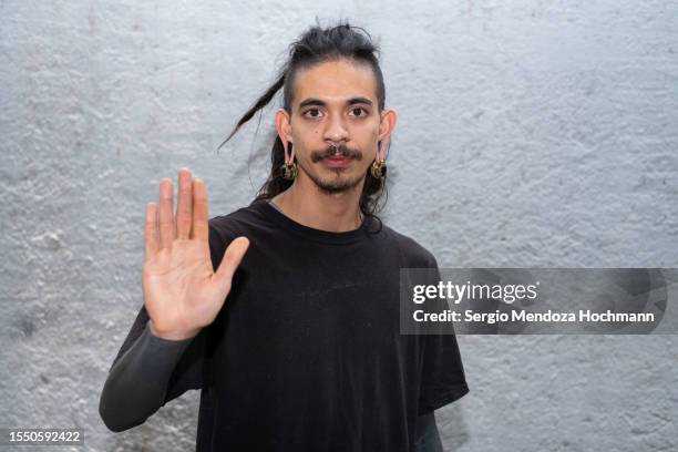 young multiracial man with long hair, dreadlocks, nose rings, piercings and sleeve tattoos looking at the camera and gesturing to stop - long hair men hairstyles fotografías e imágenes de stock