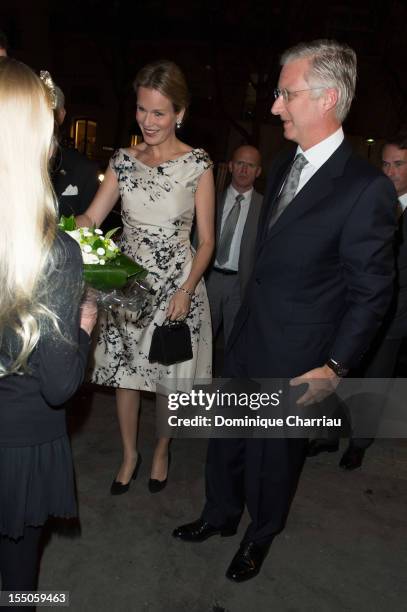 Young girl hands a bouquet of flowers to Princess Mathilde and Prince Philippe of Belgium as they arrive at Theatre des Champs-Elysees on October 31,...