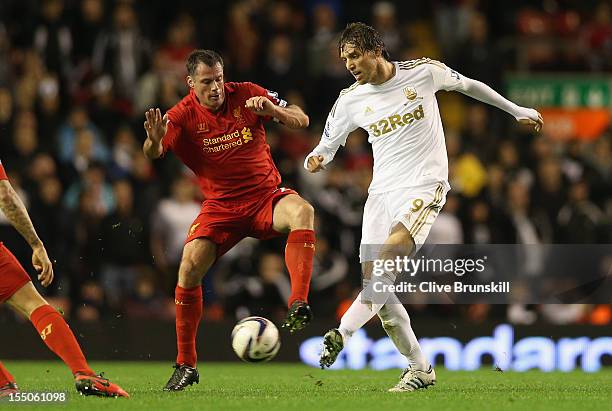 Jamie Carragher of Liverpool competes with Michu of Swansea City during the Capital One Cup Fourth Round match between Liverpool and Swansea City at...