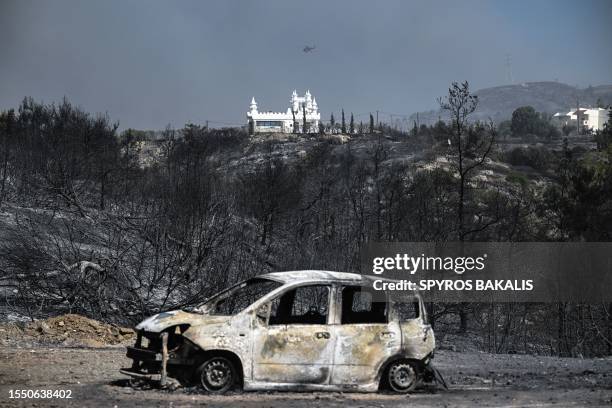 Burnt car sits in foreground of a charred area after a fire near the village of Kiotari, on the Greek island of Rhodes on July 23, 2023. Tens of...