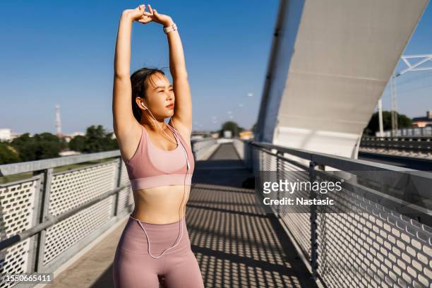 cheerful asian jogger's arm warm-up - hot arabian women stock pictures, royalty-free photos & images
