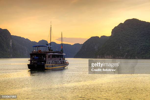 vietnamese junk cruising halong bay, hanoi vietnam sunset - halong bay stock pictures, royalty-free photos & images