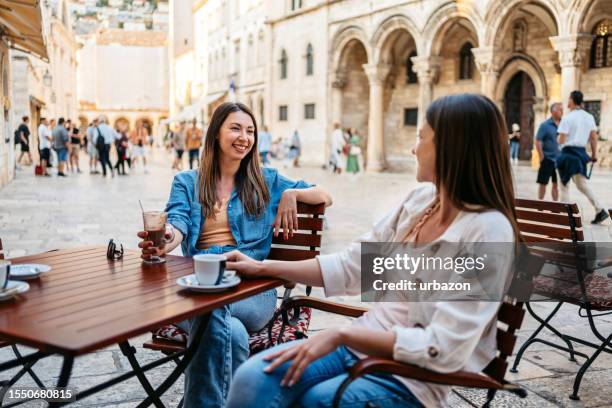 two female friends drinking coffee in a sidewalk café in dubrovnik - dubrovnik cafe stock pictures, royalty-free photos & images