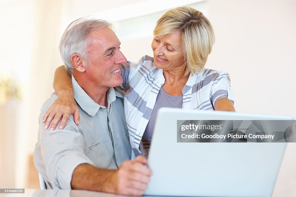 Souriant couple senior à l'aide d'un ordinateur portable