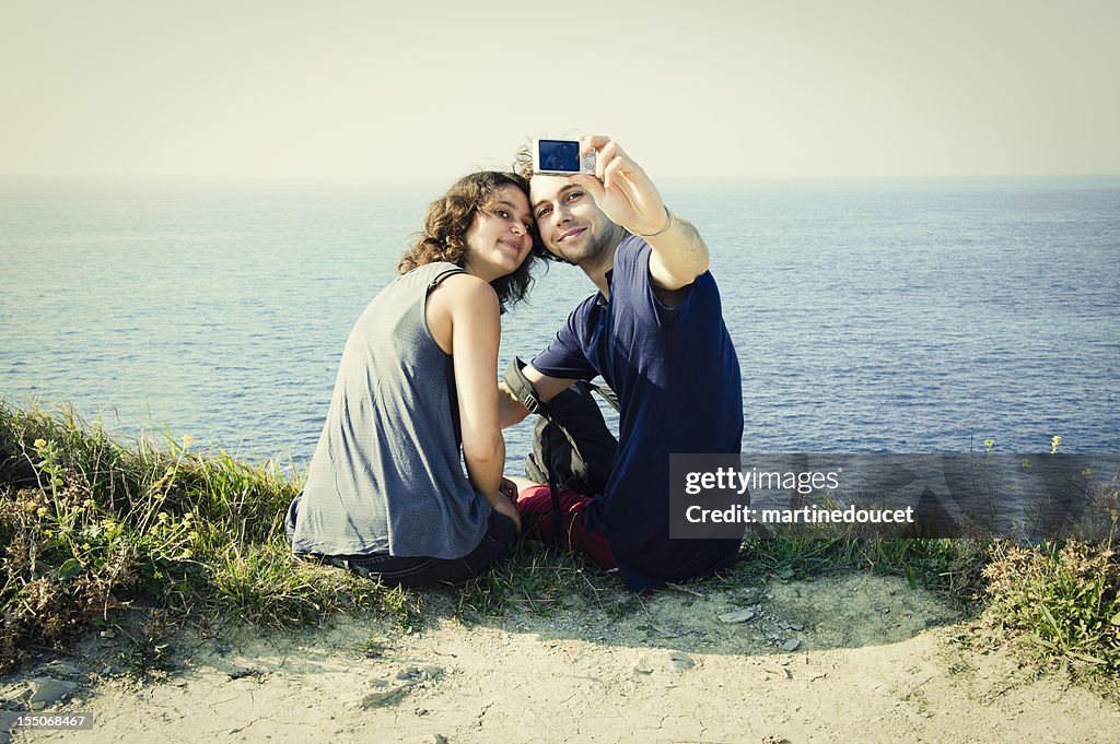 Young couple taking a photo near ocean.