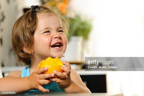 big laught - child eating a fruit stock-fotos und bilder