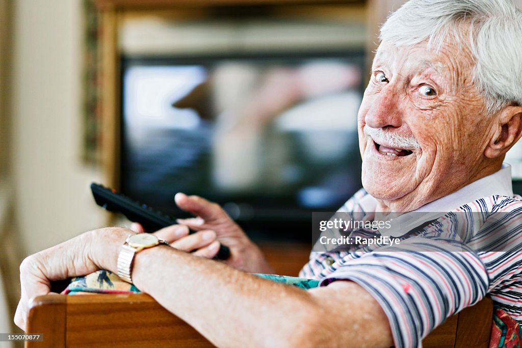 This remote control is mine! Senior man happily watching television